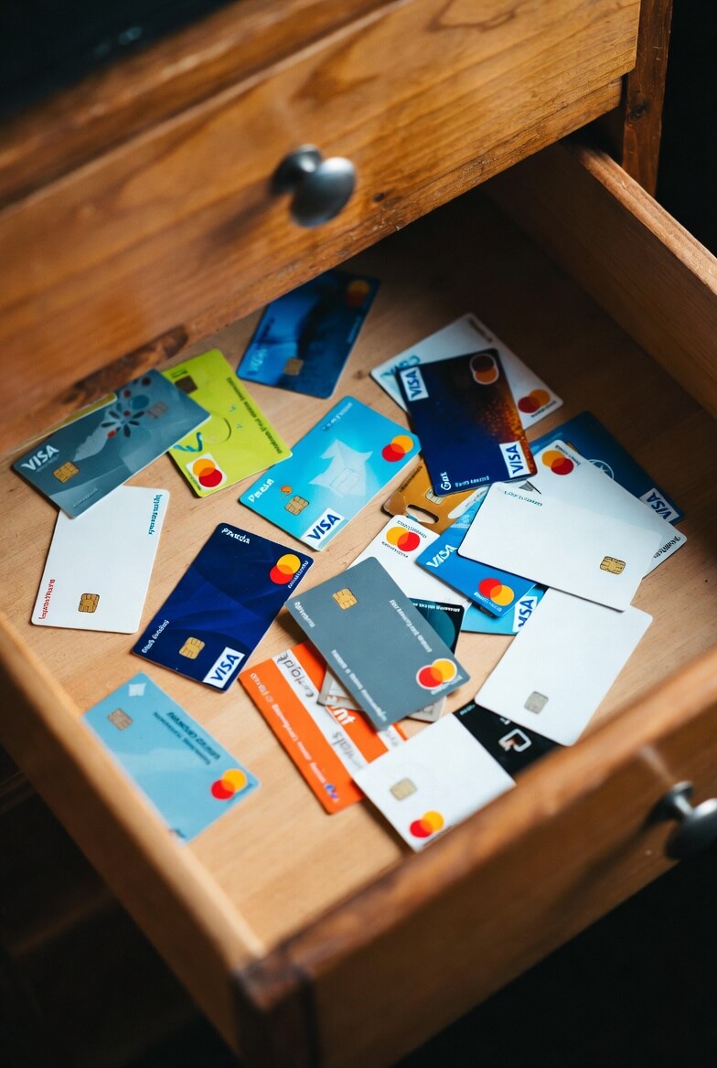Open wooden desk drawer filled with many prepaid Visa and Mastercard gift cards